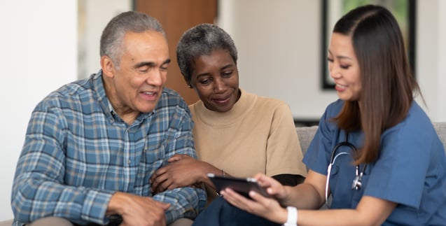 Provider talking to elderly couple and showing them patient records on iPad