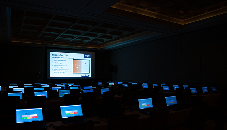Rows of laptops screens illuminate a dark room during Meditab's UGM 2023.
