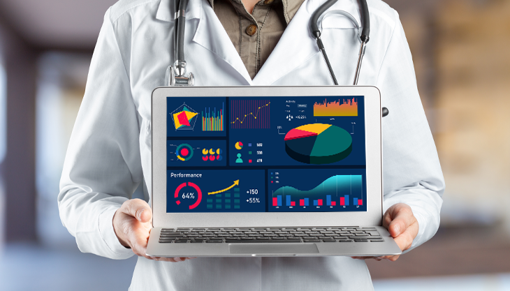 A doctor holding a laptop with the top healthcare KPIs to track in 2023 displayed on screen.