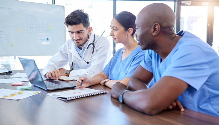 A doctor showing two other healthcare workers how their medical office software works.