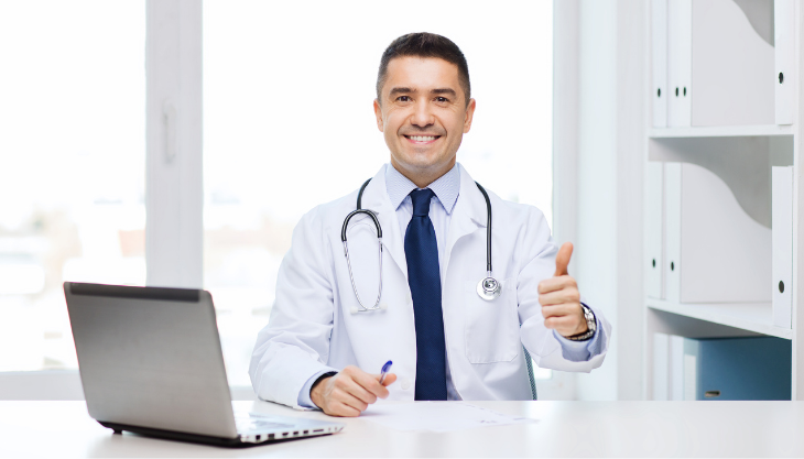 A doctor gesturing a thumbs up while on his laptop looking at healthcare KPIs.