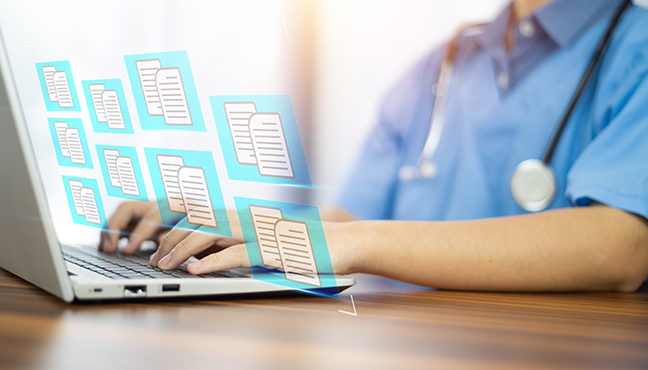 A healthcare professional typing on a laptop navigating through his EHR software.