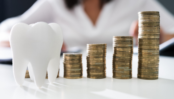 An ornamental tooth beside a stack of coins.