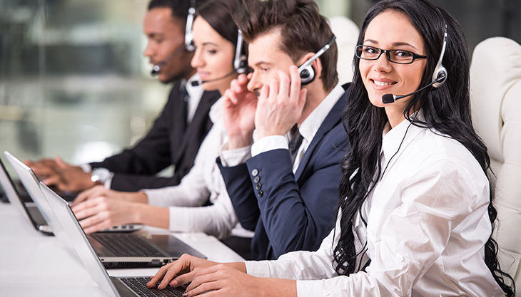 A clinical call center agent answering calls with three other colleagues in the background.