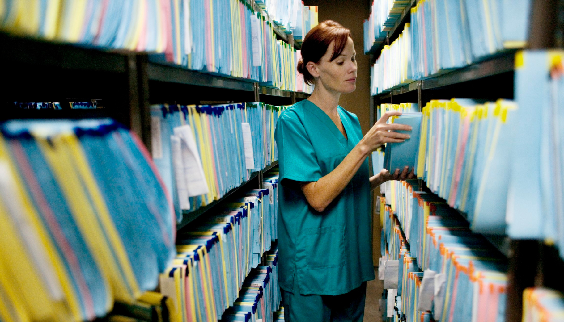 Hospital nurse looking through filed paper medical records.