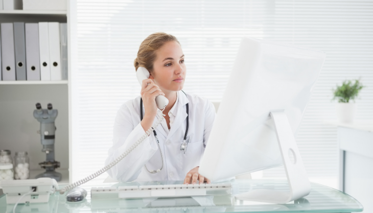 A Doctor Taking Advantage of Call Integration While on the Phone and Looking at Her EHR on the Computer