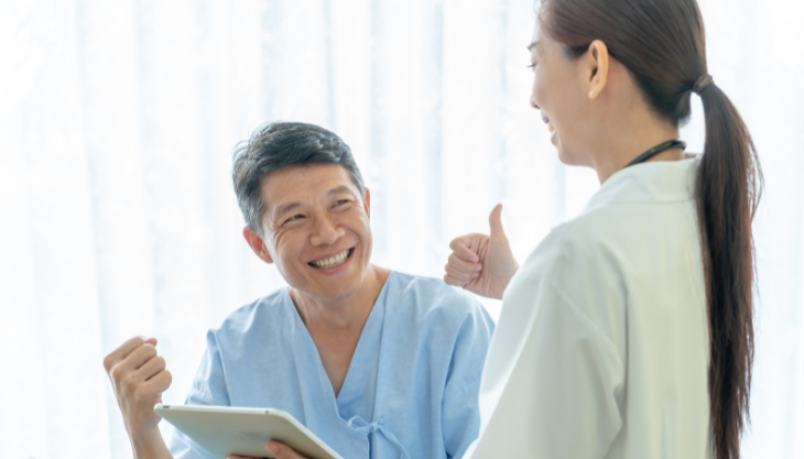 A doctor gesturing a thumbs up to a satisfied patient.