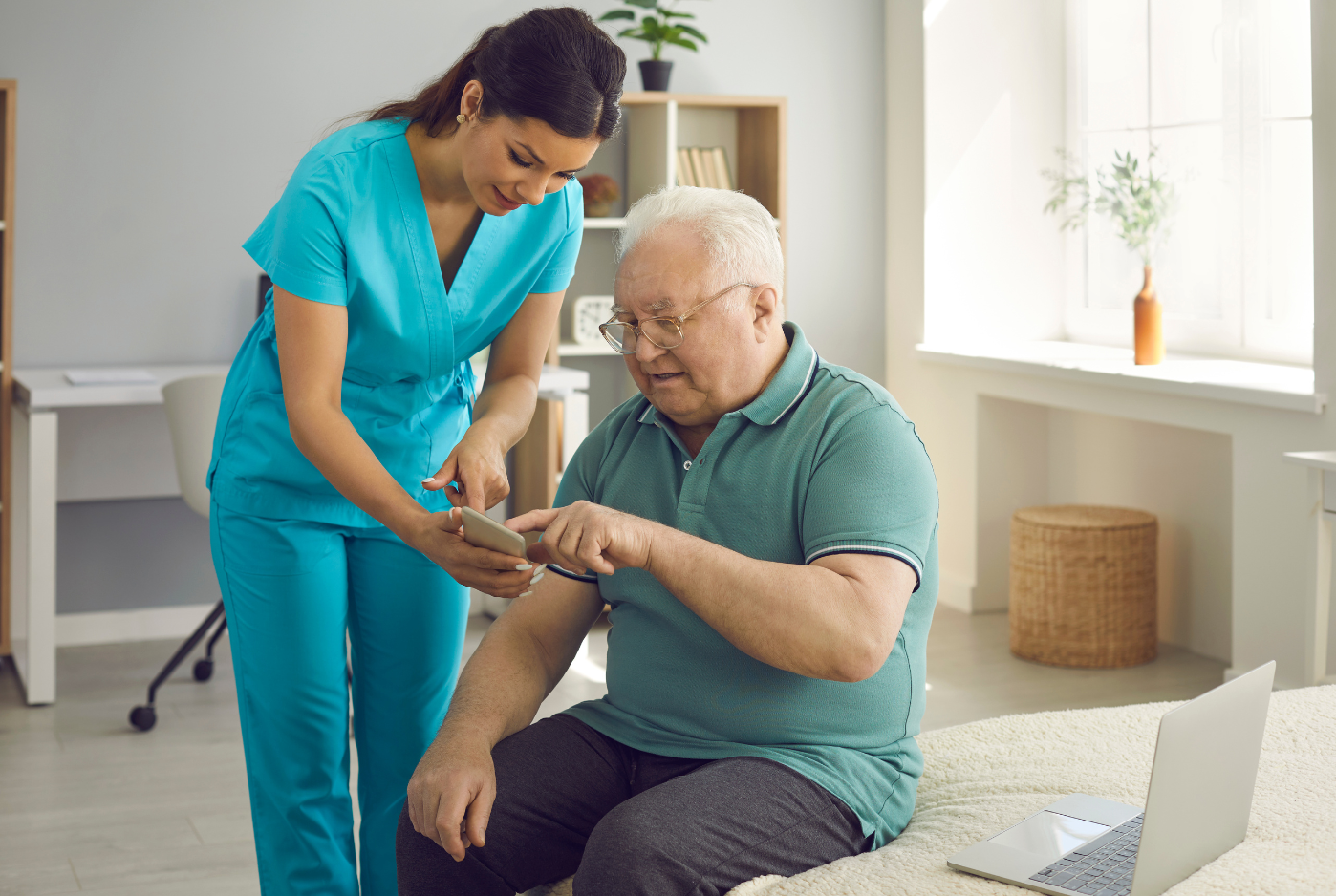 A nurse helping an elderly patient to use an app.