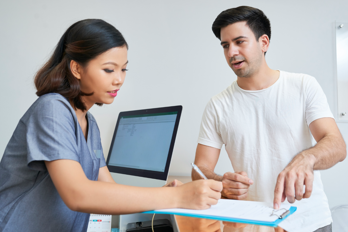 A nurse shows a clipboard to a patient and explains the care plan in detail. 