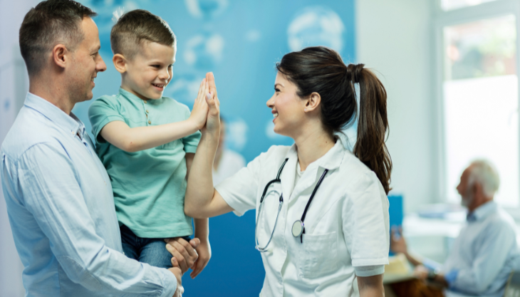 A pediatric patient giving his doctor a high five demonstrating a positive patient experience.